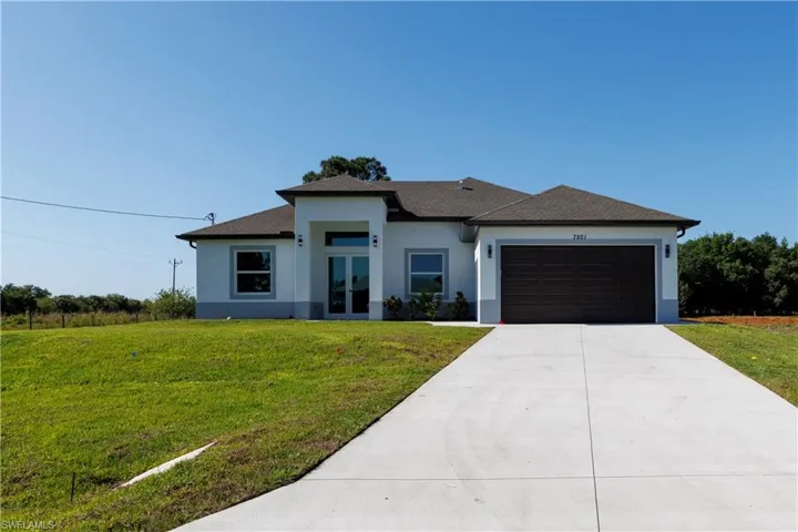 Prairie-style house with a garage, driveway, a front lawn, and stucco siding