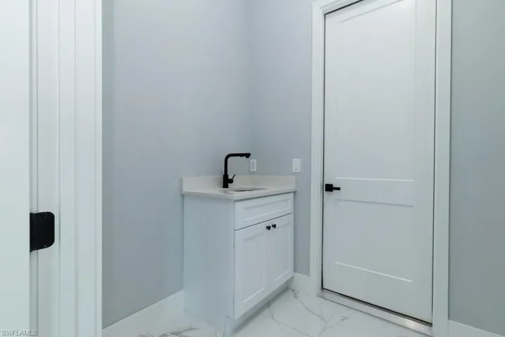 Bathroom with baseboards, marble finish floor, and vanity