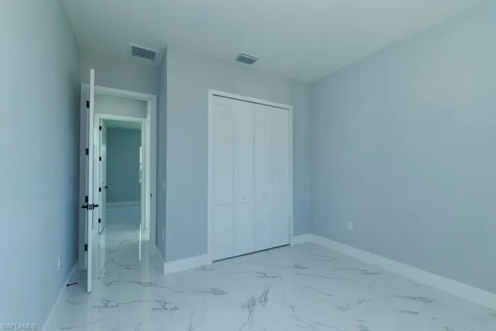 Unfurnished bedroom featuring baseboards, marble finish floor, and visible vents