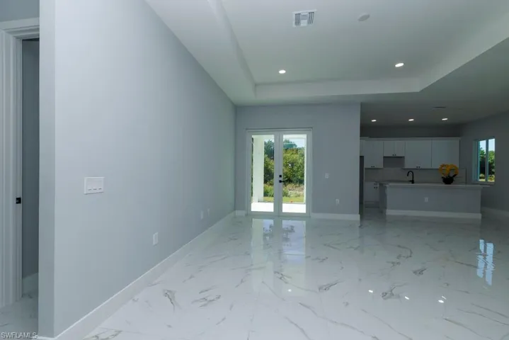 Unfurnished living room featuring baseboards, visible vents, a sink, and marble finish floor