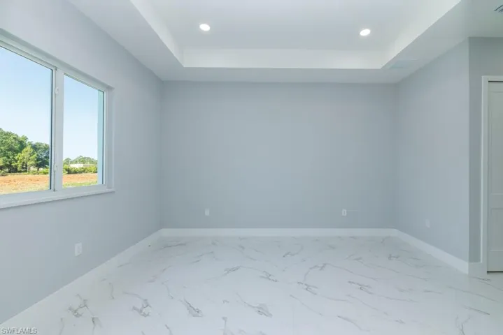 Empty room with baseboards, recessed lighting, and a raised ceiling