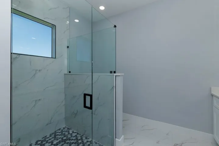 Full bathroom featuring baseboards, vanity, marble finish floor, a marble finish shower, and recessed lighting