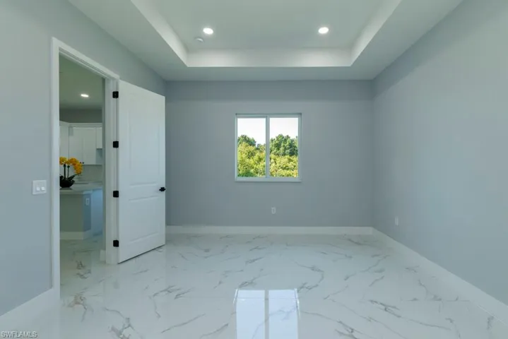 Unfurnished bedroom featuring baseboards, a tray ceiling, recessed lighting, and marble finish floor