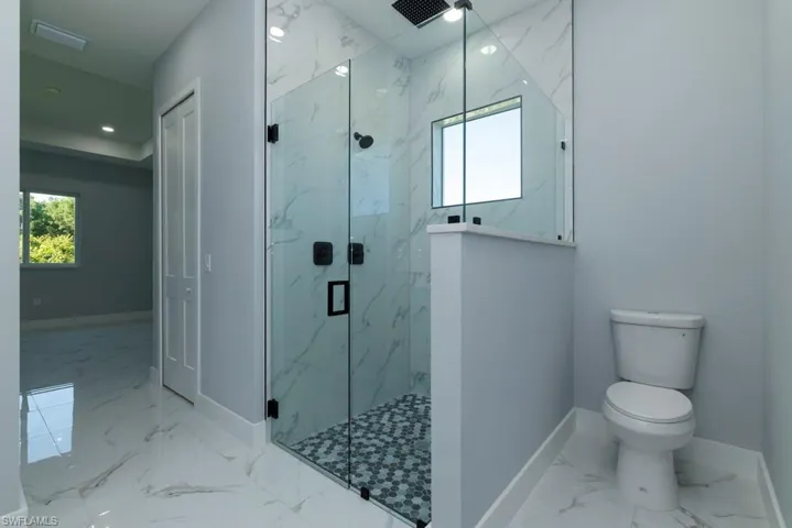 Full bathroom with baseboards, marble finish floor, a marble finish shower, and toilet
