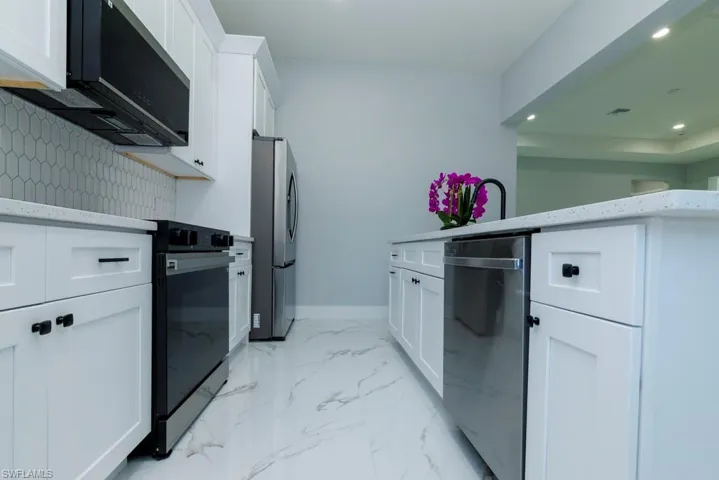 Kitchen with marble finish floor, baseboards, recessed lighting, white cabinetry, and black appliances