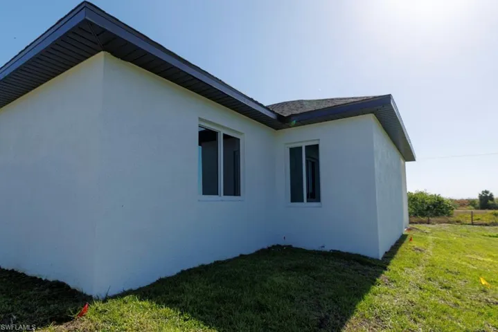 View of side of home with a yard and stucco siding
