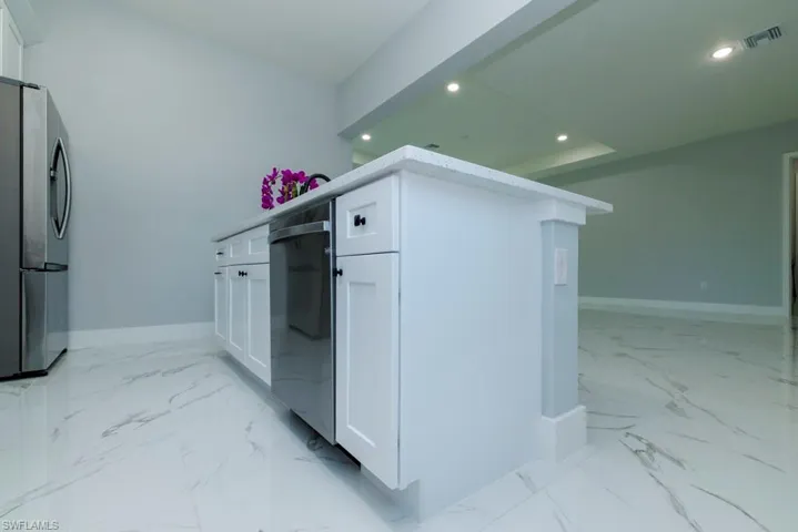 Kitchen featuring visible vents, baseboards, freestanding refrigerator, marble finish floor, and recessed lighting
