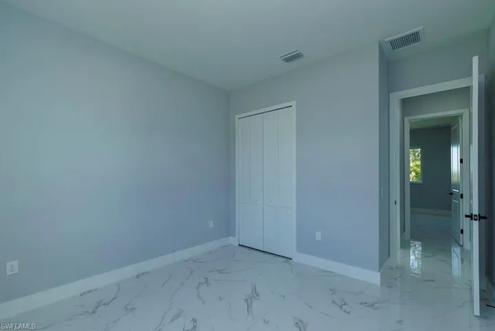 Unfurnished bedroom with baseboards, a closet, marble finish floor, and visible vents