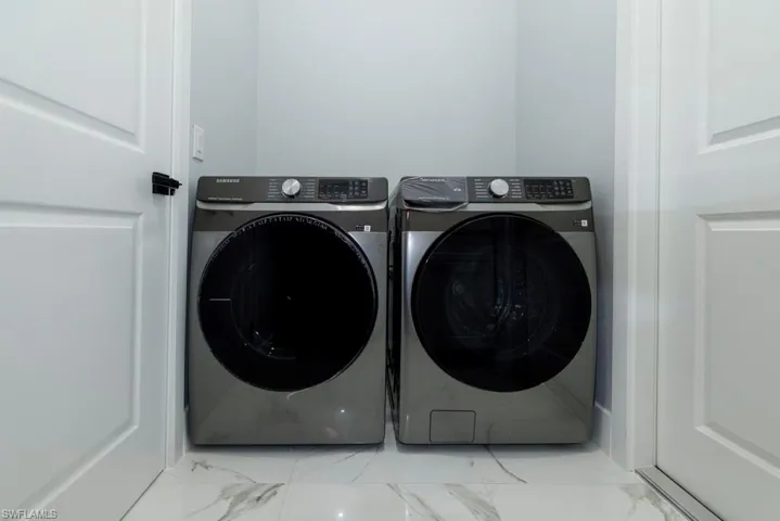 Laundry area with laundry area, marble finish floor, and washer and clothes dryer