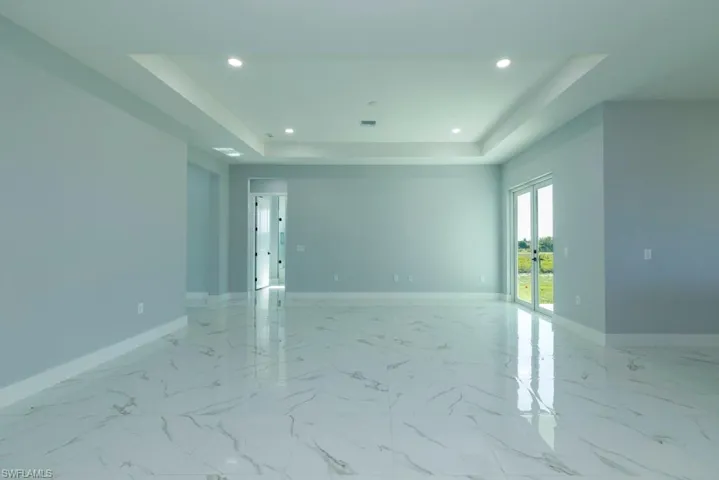 Unfurnished room featuring recessed lighting, a raised ceiling, and baseboards