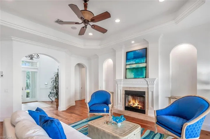 Living room with crown molding, a high end fireplace, and light wood-type flooring