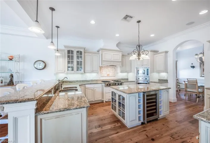 Kitchen with wine cooler, stainless steel appliances, decorative light fixtures, and kitchen peninsula