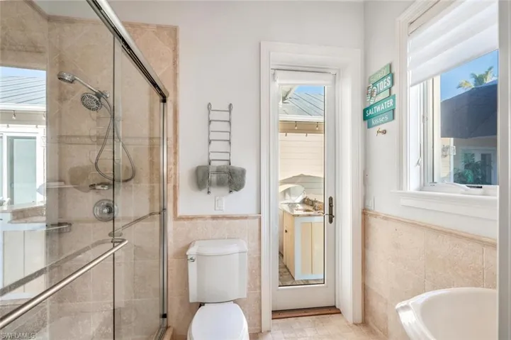 Bathroom featuring tile walls, plus walk in shower, and toilet