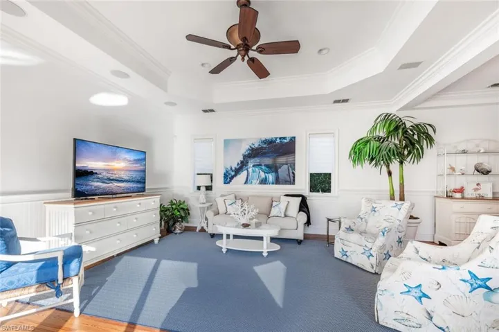 Living room featuring crown molding, ceiling fan, and a raised ceiling