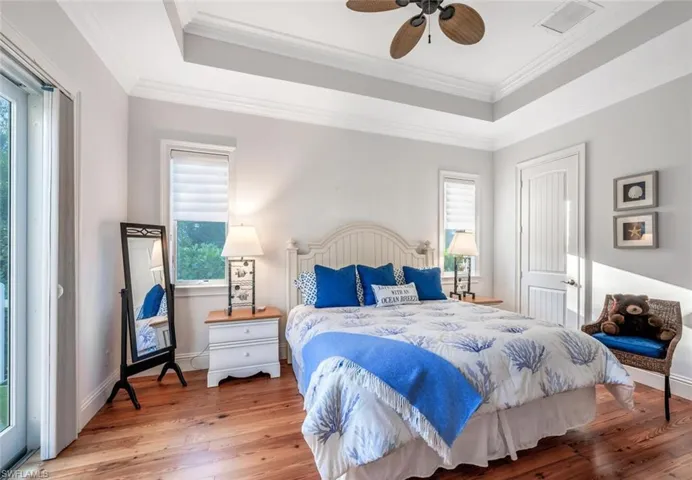Bedroom featuring crown molding, ceiling fan, wood-type flooring, and a tray ceiling