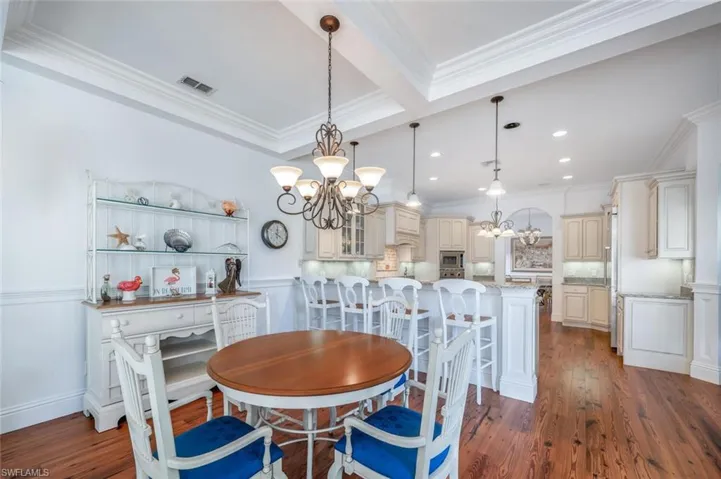 Dining space with dark wood-type flooring, ornamental molding, and a chandelier