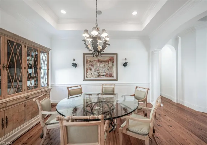 Dining room with hardwood / wood-style flooring, a tray ceiling, an inviting chandelier, and crown molding