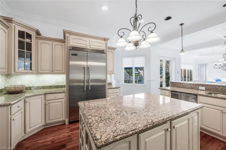 Kitchen featuring a kitchen island, appliances with stainless steel finishes, pendant lighting, an inviting chandelier, and cream cabinetry