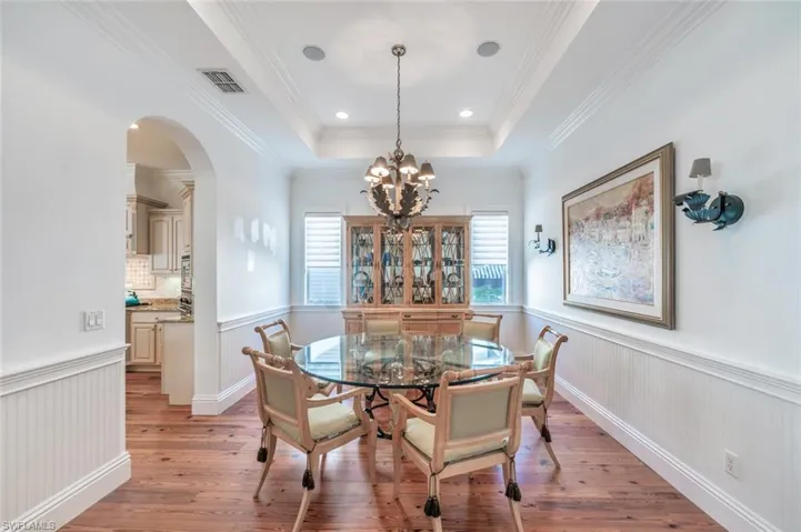 Dining area featuring ornamental molding, a notable chandelier, light wood-type flooring, and a tray ceiling
