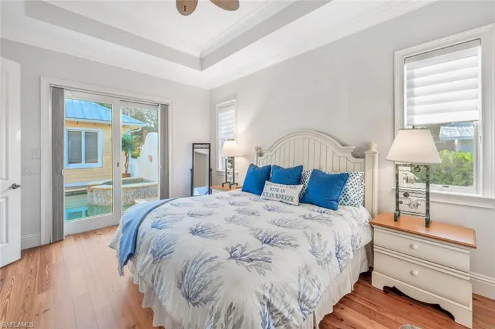 Bedroom with crown molding, access to outside, a raised ceiling, ceiling fan, and light hardwood / wood-style floors