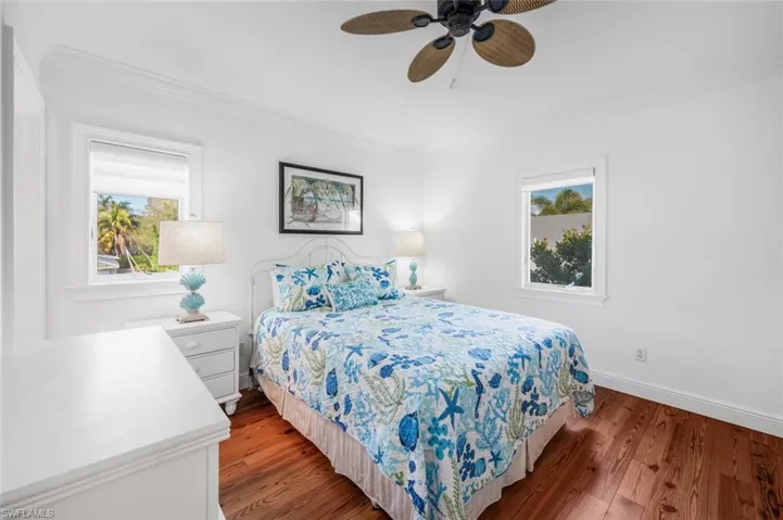 Bedroom featuring multiple windows, wood-type flooring, ornamental molding, and ceiling fan