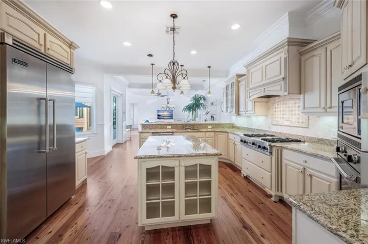 Kitchen featuring decorative light fixtures, sink, built in appliances, crown molding, and cream cabinets