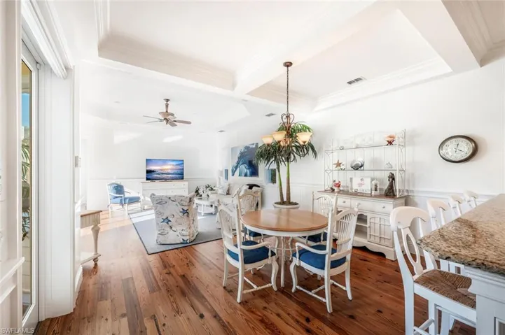Dining space featuring beam ceiling, ceiling fan with notable chandelier, ornamental molding, and dark hardwood / wood-style floors