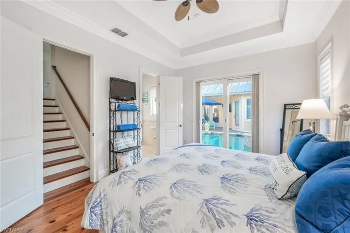 Bedroom featuring ceiling fan, hardwood / wood-style floors, ornamental molding, access to outside, and a raised ceiling