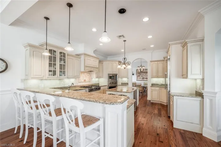 Kitchen featuring pendant lighting, stainless steel appliances, kitchen peninsula, and cream cabinetry