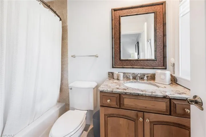 Full bathroom with vanity, shower / bath combo with shower curtain, and toilet
