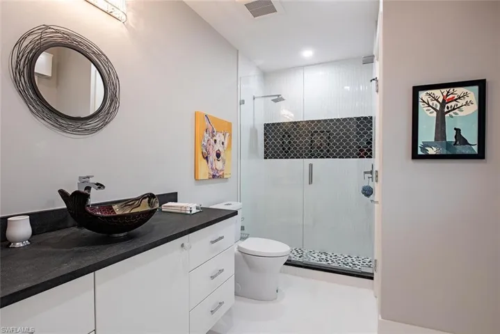 Bathroom featuring tile flooring, walk in shower, vanity, and toilet