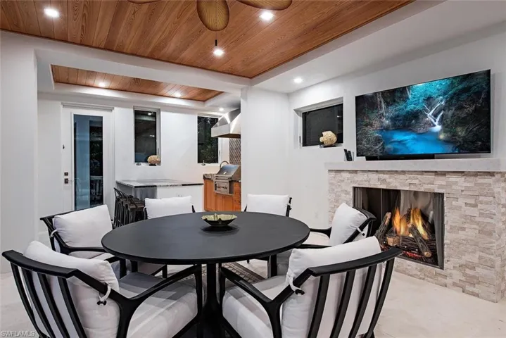 Dining room with wooden ceiling, a fireplace, ceiling fan, and a raised ceiling