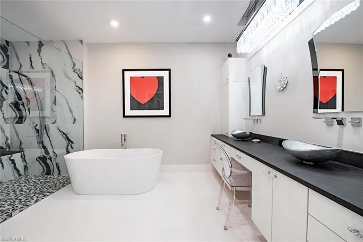 Bathroom with tiled shower, double vanity, and tile floors