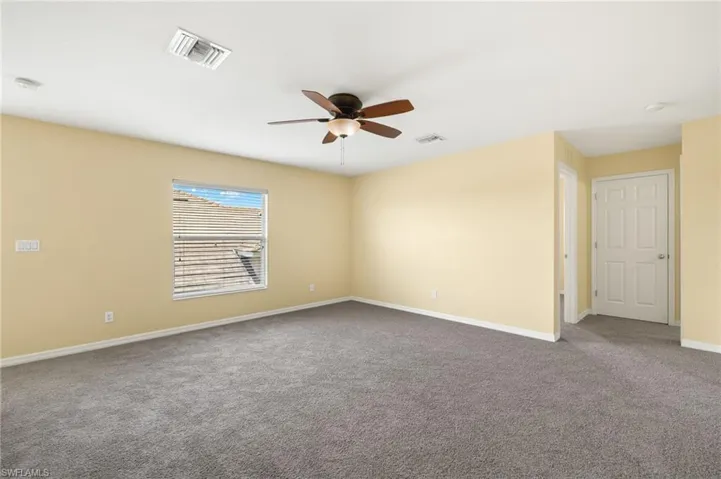 Unfurnished room with carpet floors, ceiling fan, baseboards, and a smoke detector