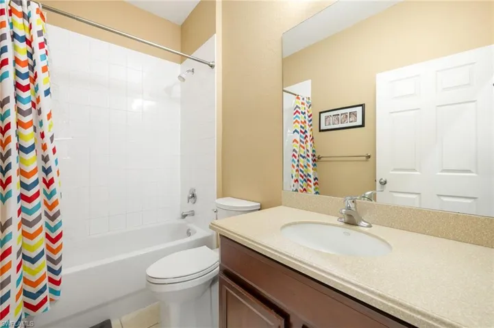Bathroom with vanity, shower / bathtub combination with curtain, and toilet