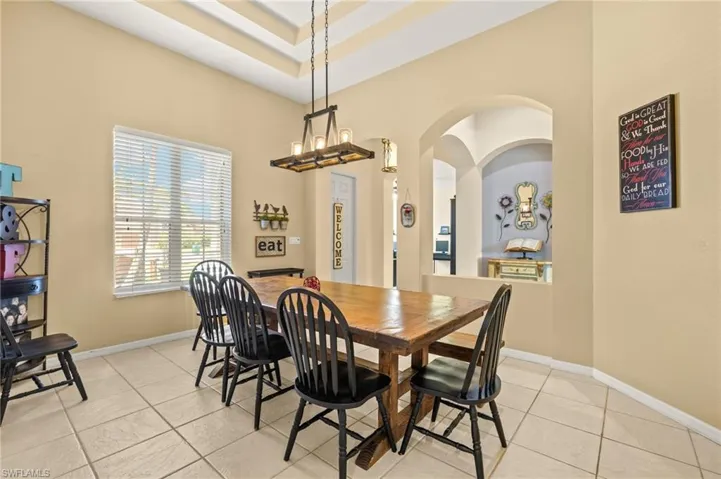 Dining area with arched walkways, light tile patterned floors, and baseboards