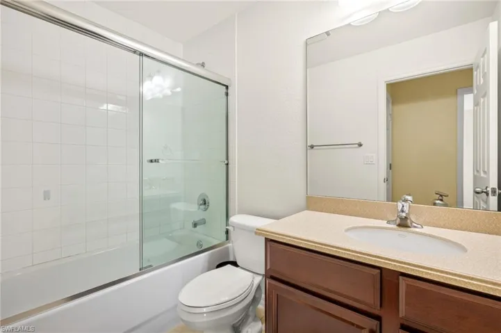 Full bath with toilet, vanity, and combined bath / shower with glass door