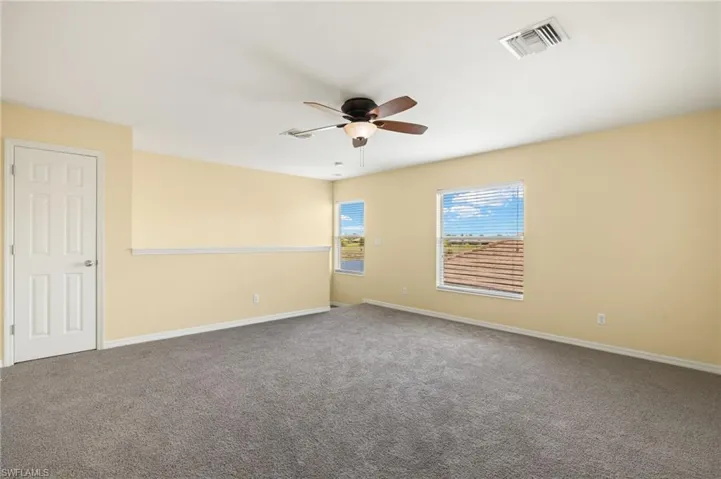 Carpeted empty room featuring ceiling fan and baseboards