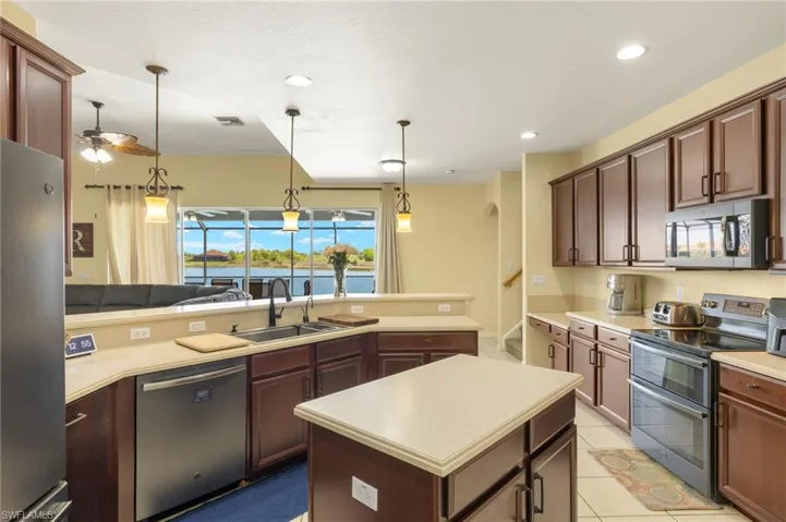 Kitchen featuring stainless steel appliances, a sink, light countertops, ceiling fan, and recessed lighting