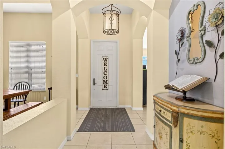 Entryway featuring light tile patterned floors, arched walkways, and baseboards