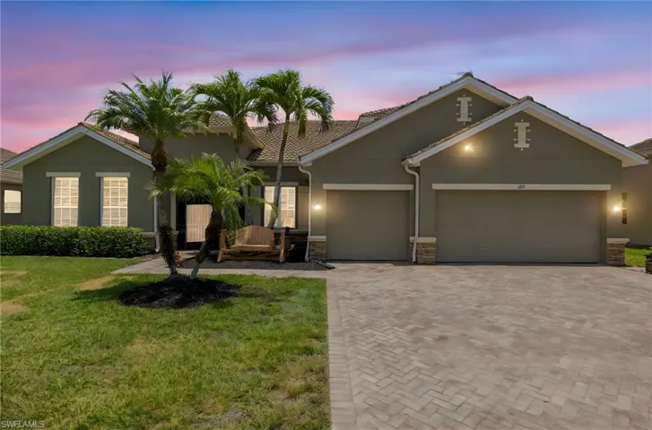 View of front of house featuring stucco siding, an attached garage, decorative driveway, a lawn, and stone siding