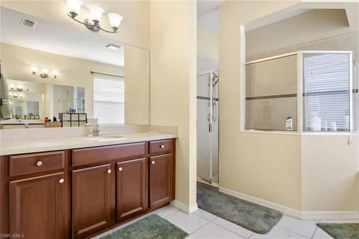 Full bath with a stall shower, tile patterned floors, vanity, and baseboards