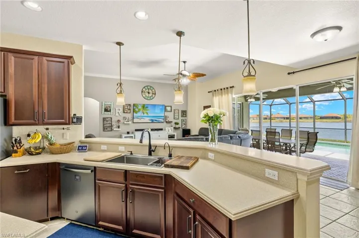 Kitchen featuring stainless steel dishwasher, a ceiling fan, light countertops, a sink, and ornamental molding