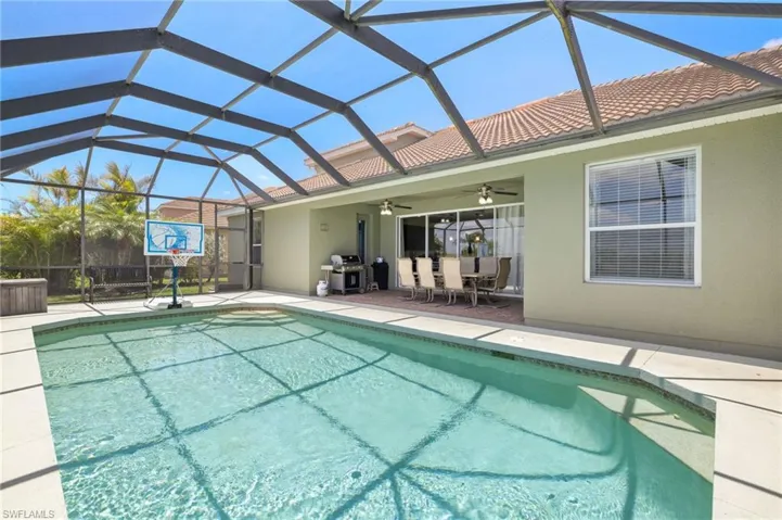 Outdoor pool featuring a ceiling fan, a patio area, grilling area, and a lanai