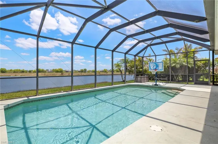 Swimming pool with a water view, a patio area, and a lanai
