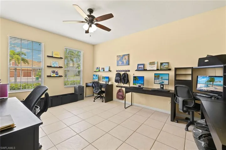 Office with ceiling fan, plenty of natural light, tile patterned floors, and baseboards