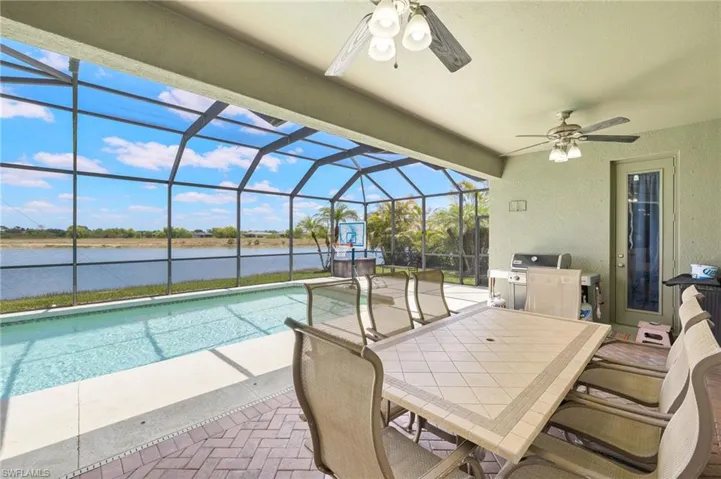 View of patio featuring a ceiling fan, a water view, area for grilling, and an outdoor pool