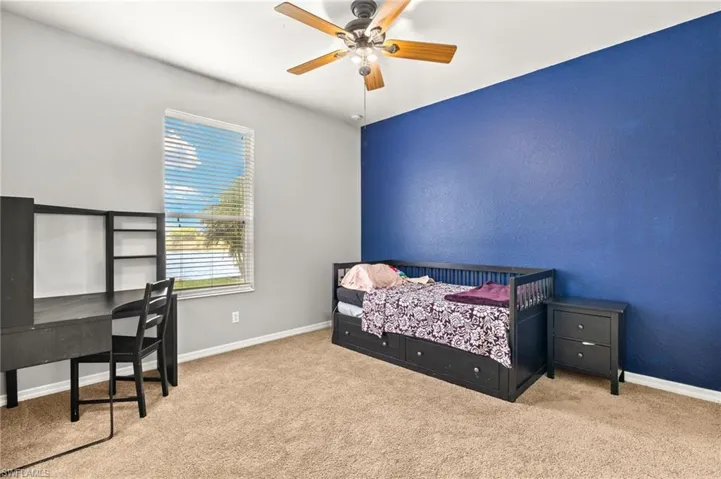 Carpeted bedroom with baseboards, a desk, and ceiling fan