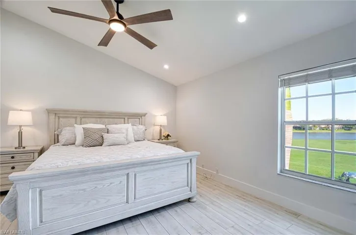 Bedroom featuring vaulted ceiling, a water view, a ceiling fan, light wood finished floors, and recessed lighting