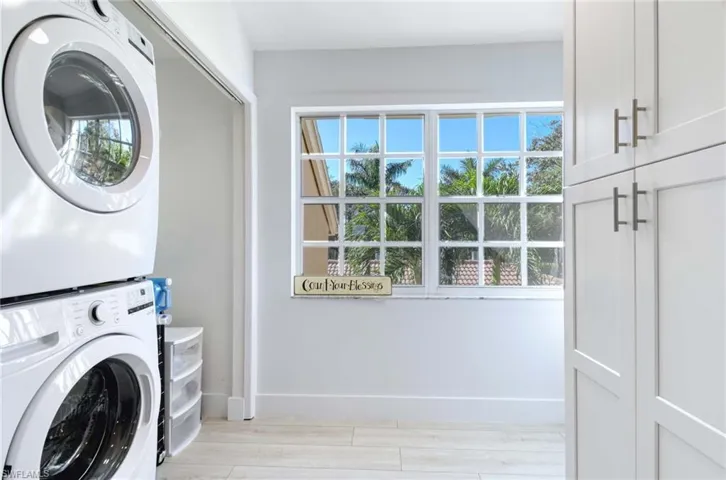 Laundry area featuring estacked washer and dryer and light wood-type flooring